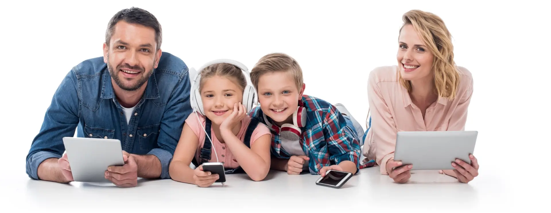 Family smiling with digital devices, lying down.